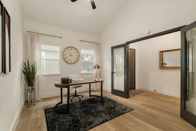 office space with light wood-type flooring, baseboards, ceiling fan, and high vaulted ceiling