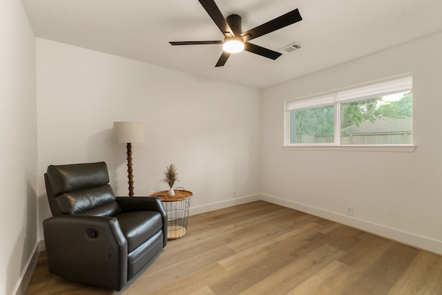 sitting room featuring baseboards, a ceiling fan, and light wood-style flooring