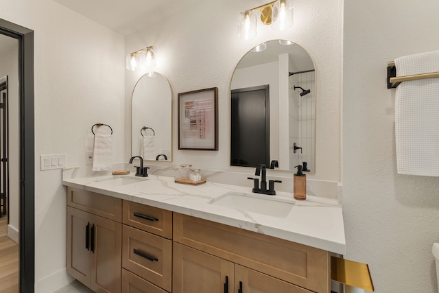full bath with a sink, a shower, and double vanity