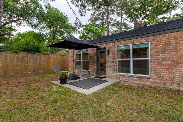 rear view of house with brick siding, fence, and a patio area
