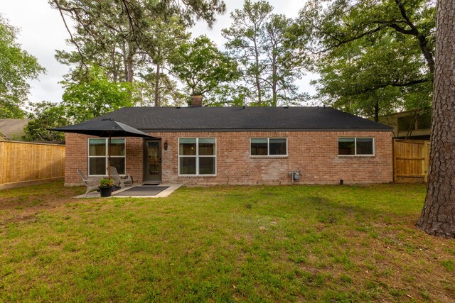 rear view of property featuring a fenced backyard, a lawn, a patio area, and brick siding