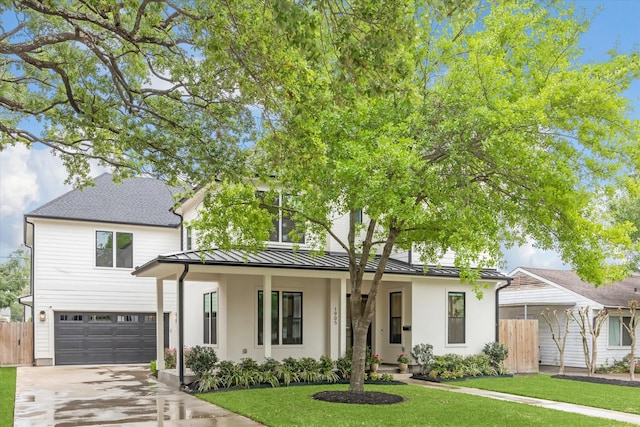 view of front of house featuring a standing seam roof, a front yard, fence, concrete driveway, and an attached garage