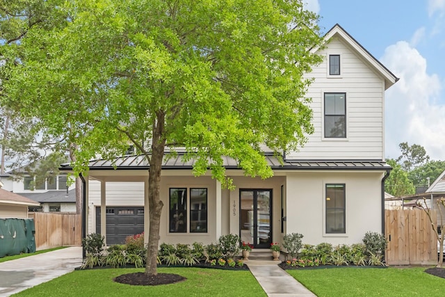 view of front facade featuring fence, a front yard, concrete driveway, a standing seam roof, and metal roof