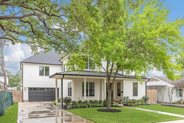 view of front of home with a standing seam roof, fence, concrete driveway, and a front lawn