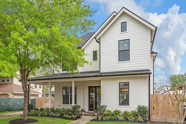 view of front of home with a standing seam roof, fence, covered porch, and metal roof
