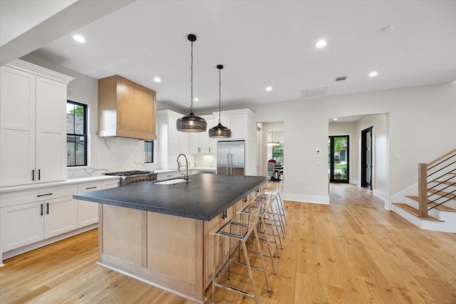 kitchen featuring a kitchen island with sink, a breakfast bar area, recessed lighting, stainless steel built in fridge, and a sink