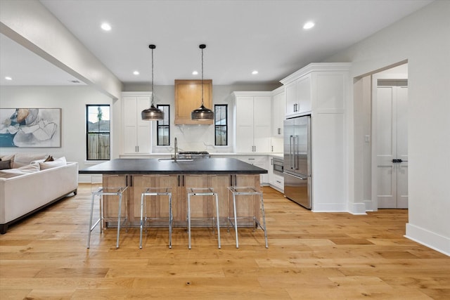 kitchen featuring stainless steel built in fridge, dark countertops, open floor plan, recessed lighting, and white cabinetry