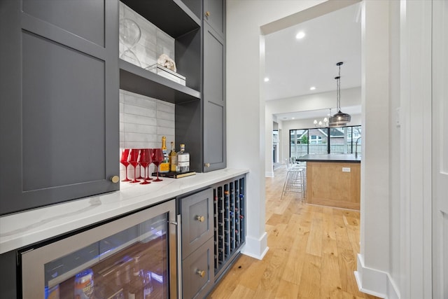 hall with recessed lighting, baseboards, light wood finished floors, and beverage cooler