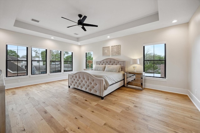 bedroom with visible vents, multiple windows, and a raised ceiling