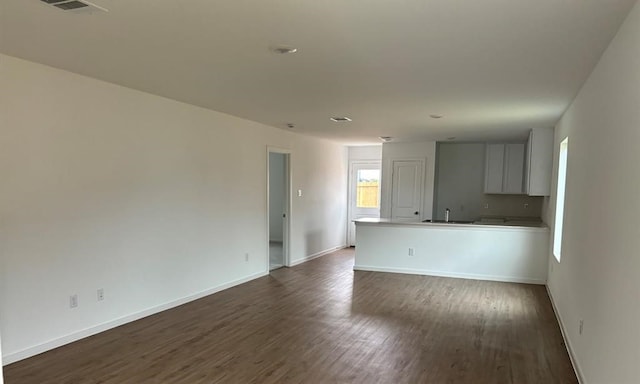 spare room featuring baseboards, visible vents, dark wood-style floors, and a sink
