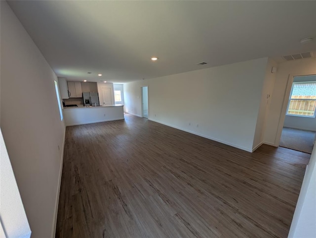 unfurnished living room with recessed lighting, baseboards, dark wood-style flooring, and visible vents