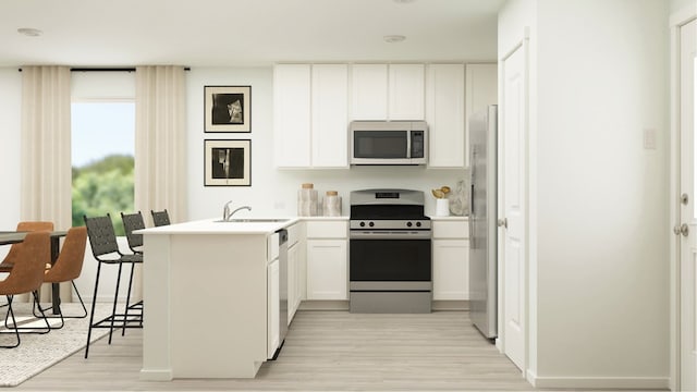 kitchen with a sink, stainless steel appliances, a peninsula, and light wood-style flooring