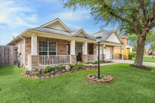 view of front of property featuring fence, covered porch, an attached garage, and a front yard