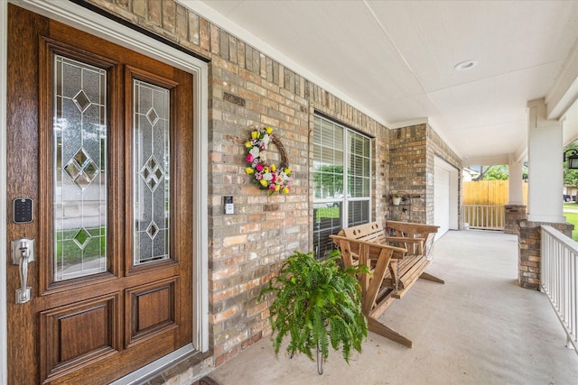 entrance to property with a porch and brick siding