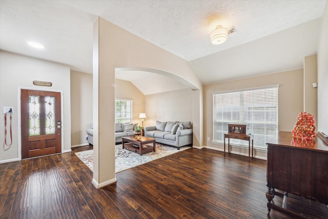 entryway featuring arched walkways, baseboards, wood finished floors, and lofted ceiling