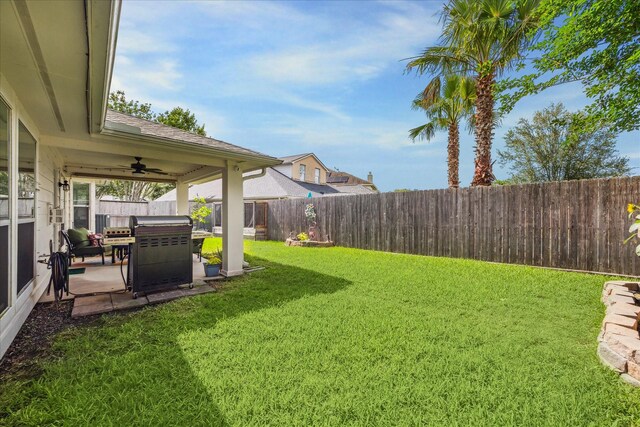 view of yard with a fenced backyard, ceiling fan, and a patio area