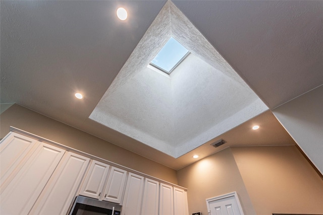 interior details with white cabinets, stainless steel microwave, recessed lighting, and visible vents