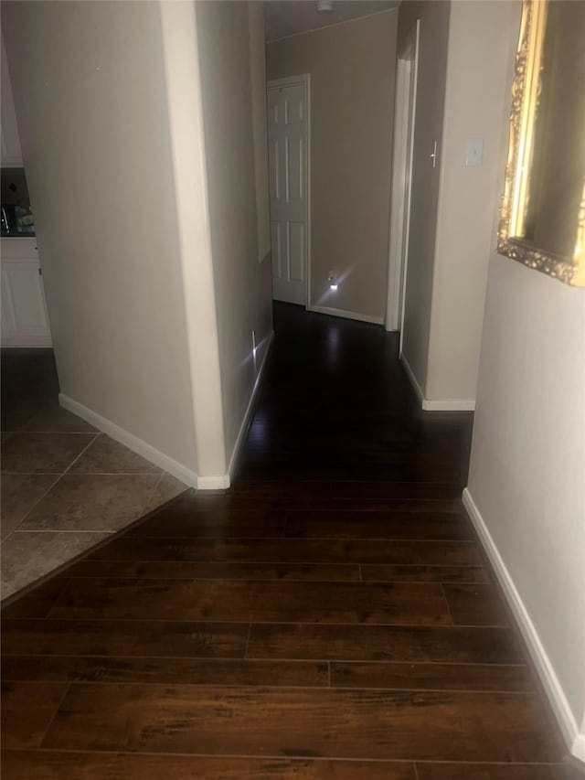 corridor with baseboards and wood-type flooring