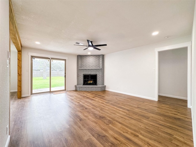 unfurnished living room featuring baseboards, ceiling fan, wood finished floors, and a fireplace