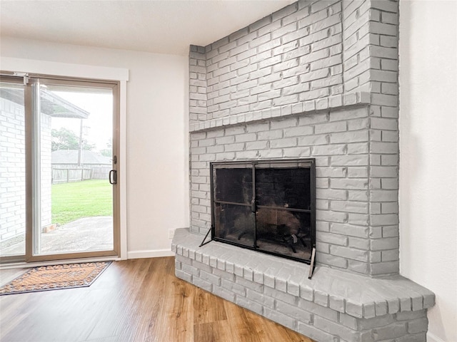 interior space featuring a brick fireplace, baseboards, and wood finished floors