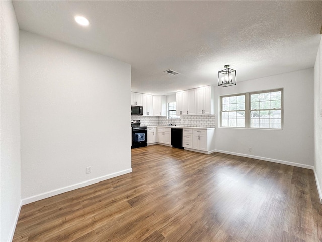 kitchen featuring backsplash, visible vents, wood finished floors, black appliances, and a notable chandelier