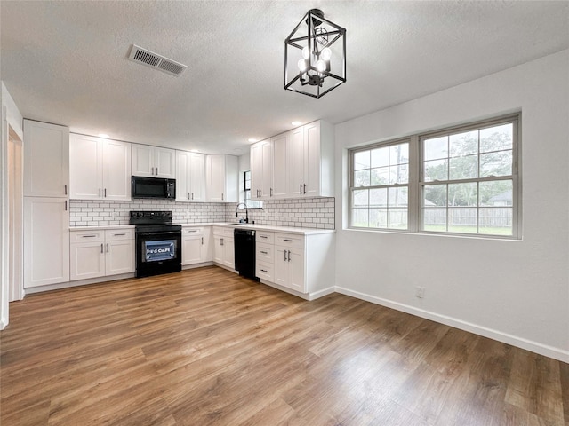 kitchen with visible vents, light countertops, backsplash, and black appliances