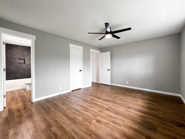 unfurnished bedroom with ceiling fan, baseboards, ensuite bathroom, and wood finished floors