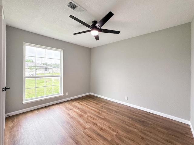 spare room with visible vents, baseboards, and wood finished floors