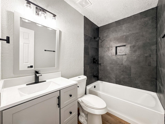 bathroom featuring a textured wall, vanity, toilet, wood finished floors, and visible vents