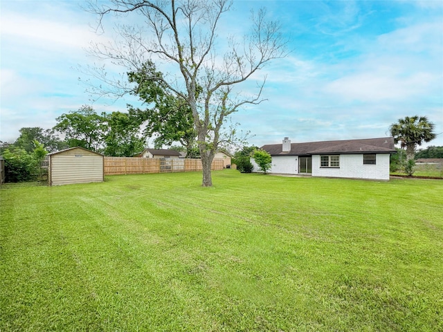 view of yard with a storage shed, fence, and an outbuilding