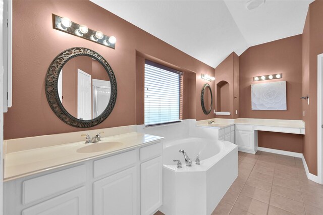 bathroom with lofted ceiling, a bath, tile patterned floors, two vanities, and a sink