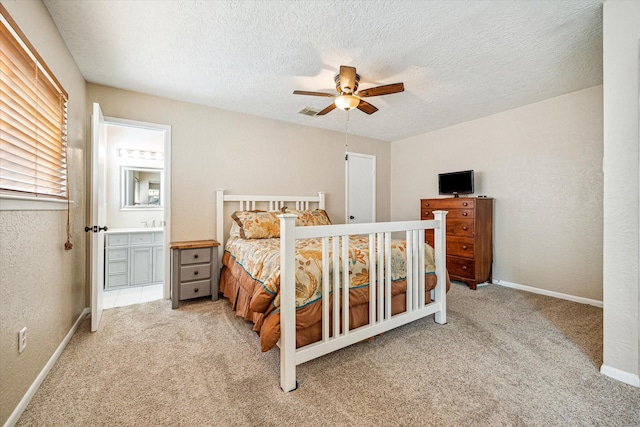 carpeted bedroom with a textured wall, baseboards, ceiling fan, a textured ceiling, and ensuite bath