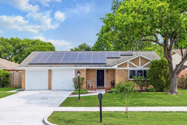 view of front of home featuring an attached garage, a front lawn, roof mounted solar panels, and concrete driveway