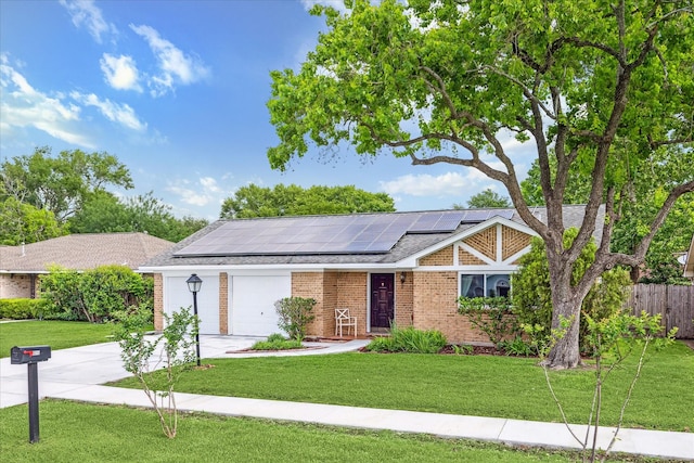 ranch-style house featuring solar panels, brick siding, a front lawn, concrete driveway, and an attached garage