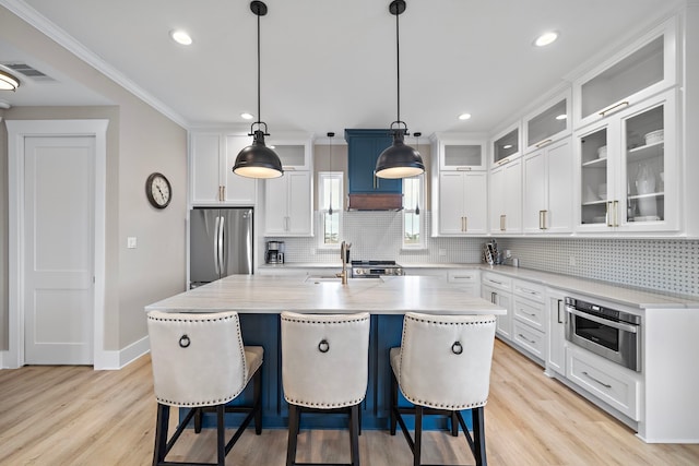 4014 Miramar Ct, Galveston, TX 77554 - kitchen featuring a sink, light wood-style flooring, stainless steel appliances, tasteful backsplash, and a center island with sink