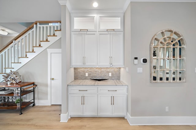 4014 Miramar Ct, Galveston, TX 77554 - bar with crown molding, light wood finished floors, baseboards, decorative backsplash, and stairway