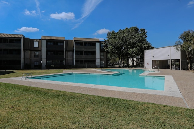 community pool featuring a lawn, a patio area, and fence