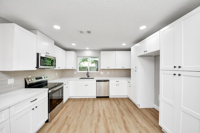 16315 Summer Dew Ln, Houston, TX 77095 - kitchen with appliances with stainless steel finishes, light wood-style flooring, a sink, tasteful backsplash, and recessed lighting