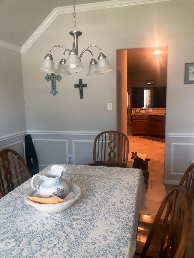 dining room with a wainscoted wall, ornamental molding, a decorative wall, and lofted ceiling