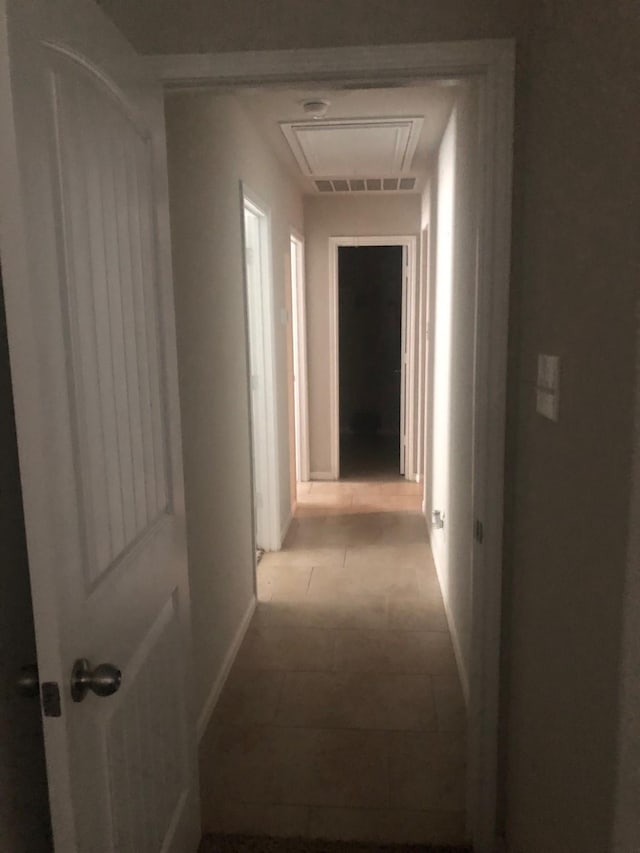 hall with baseboards, attic access, and visible vents