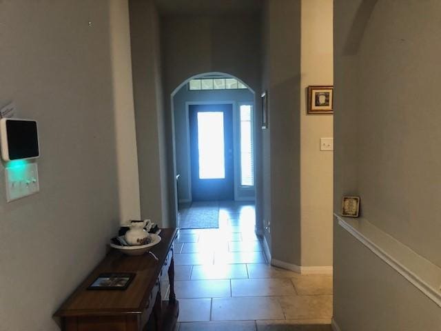 interior space with arched walkways and light tile patterned floors