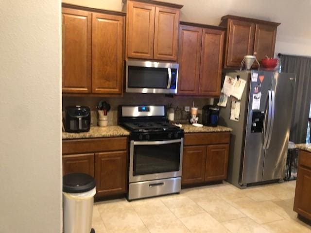 kitchen with light stone counters and appliances with stainless steel finishes