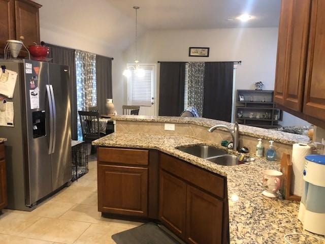 kitchen featuring a sink, lofted ceiling, light stone countertops, and stainless steel fridge with ice dispenser