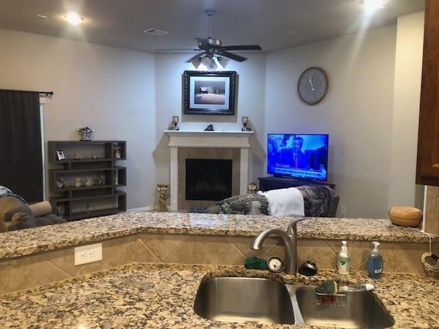 living room with a fireplace, a ceiling fan, and visible vents