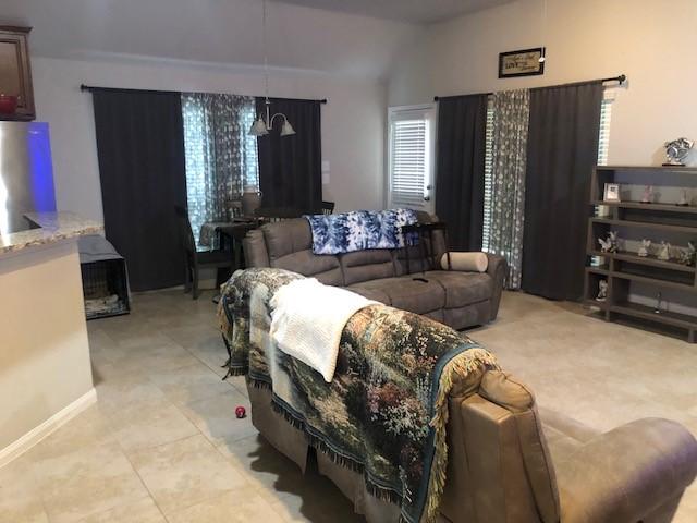 living room featuring baseboards, light tile patterned floors, and lofted ceiling