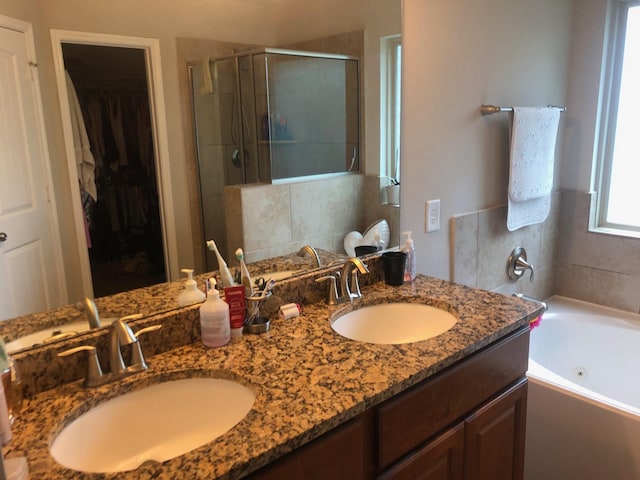bathroom with a sink, a whirlpool tub, a shower stall, and double vanity
