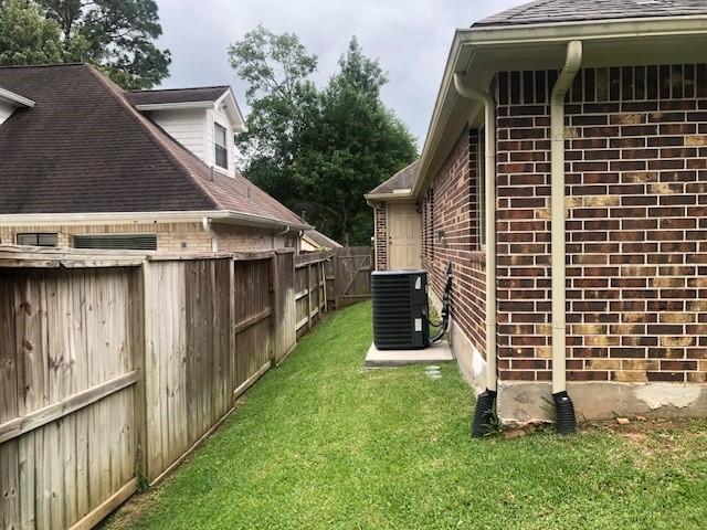 view of property exterior with a yard, brick siding, cooling unit, and a fenced backyard
