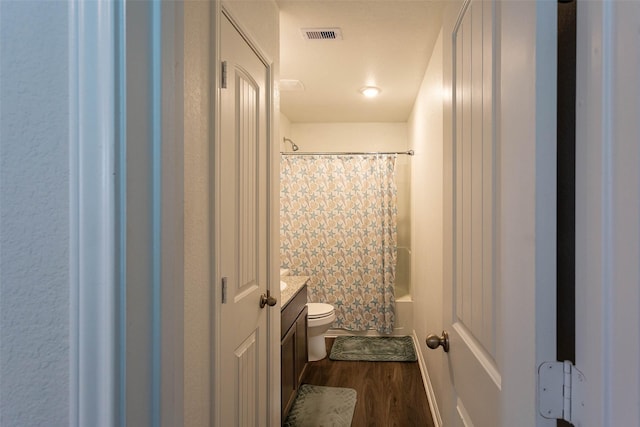 full bath featuring vanity, toilet, shower / bath combo with shower curtain, wood finished floors, and visible vents