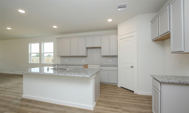 4439 Azalea Blossom Rd, Pinehurst, TX 77362 - kitchen featuring a center island with sink, visible vents, tasteful backsplash, and light wood-style floors