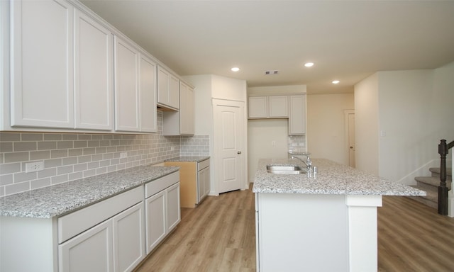 4439 Azalea Blossom Rd, Pinehurst, TX 77362 - kitchen featuring a center island with sink, recessed lighting, a sink, light wood-style flooring, and backsplash